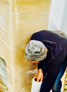 Person in black jacket applying yellow coating to wooden wall surface