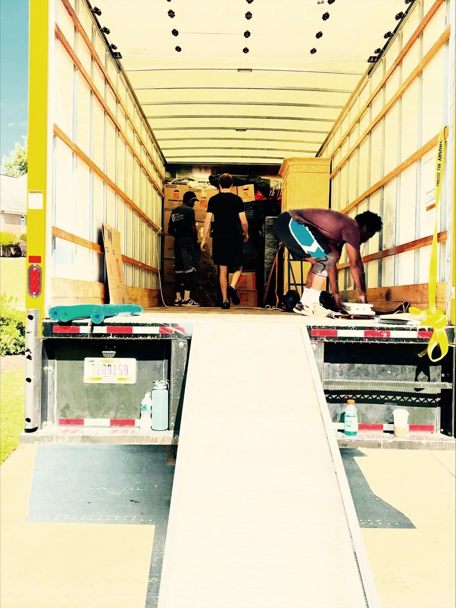 Workers loading boxes into a moving truck with bright yellow frame and wooden interior