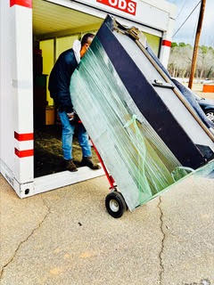 Worker unloading large window pane from white delivery truck