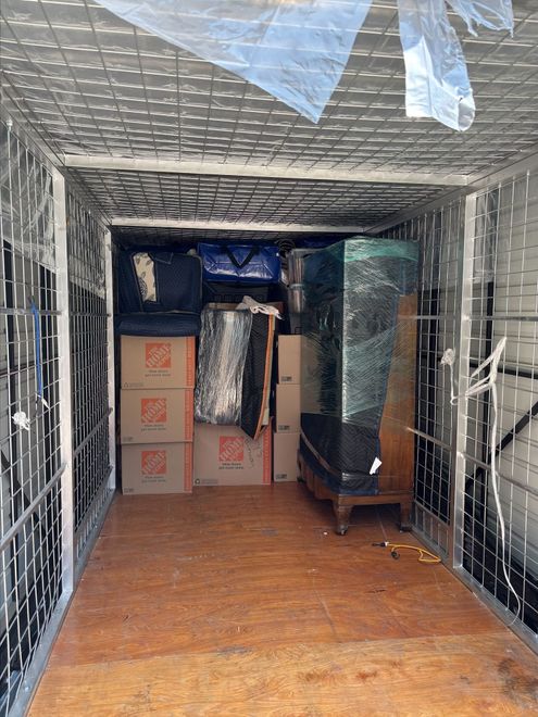 Interior of moving truck loaded with cardboard boxes and furniture wrapped in plastic